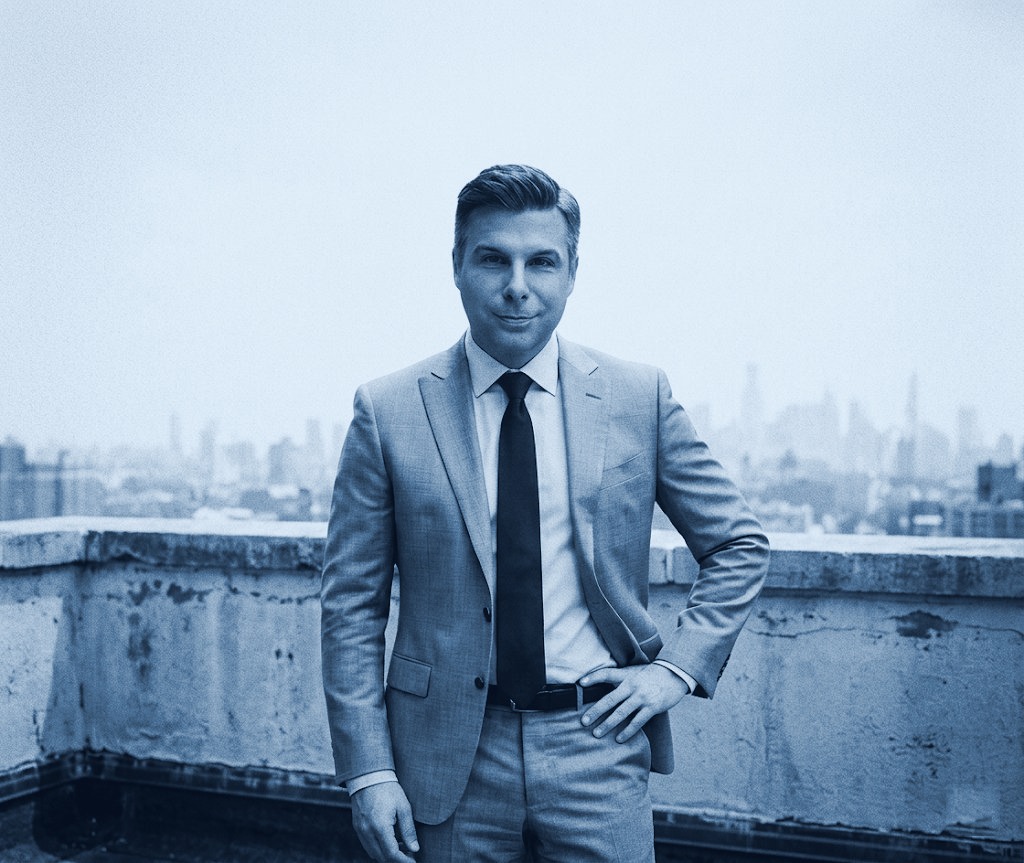 Cory Chamberlain, publicist and author, on a rooftop with the city skyline behind